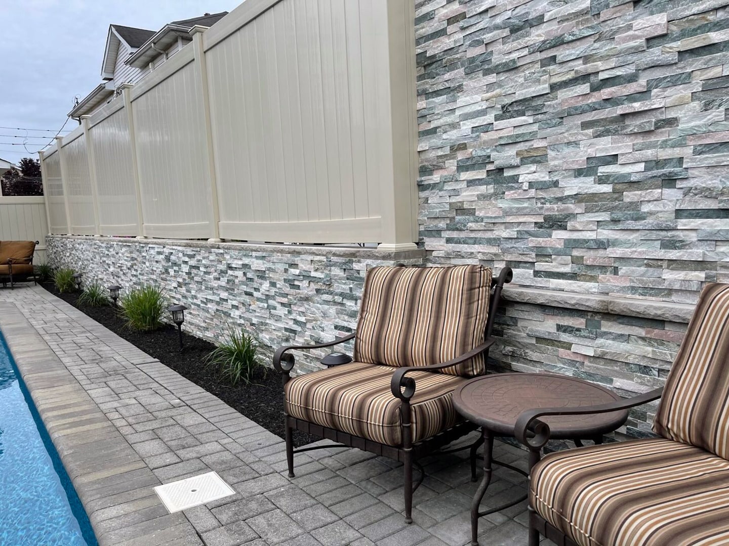 Front yard with iron gates, stone pillars, planting beds and lawn