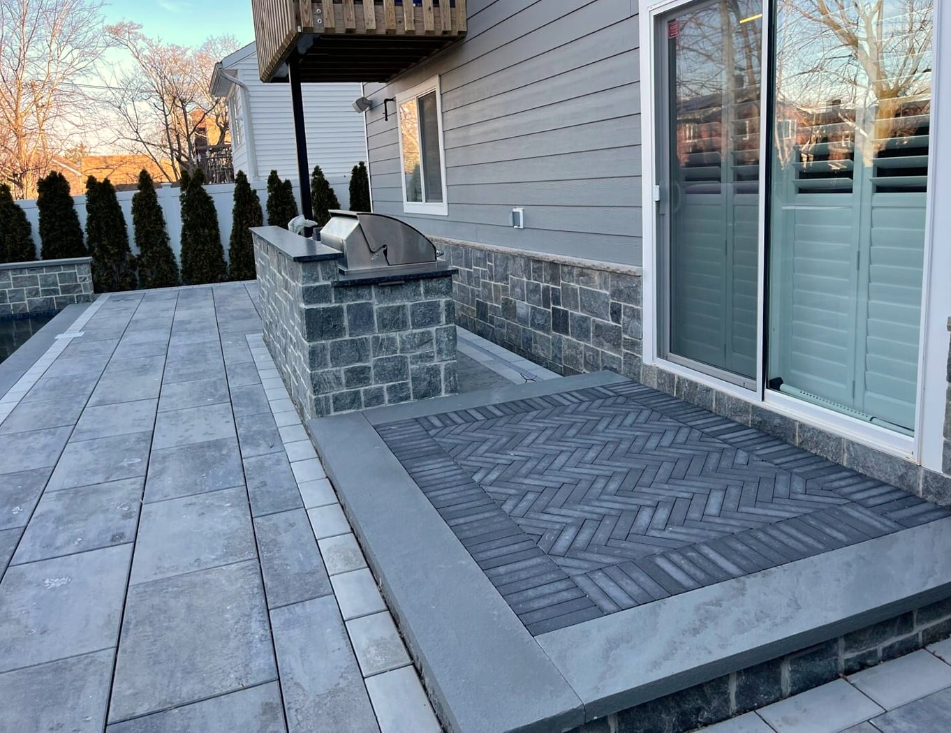 Two cushioned chairs by pool, stacked stone wall and vinyl fence
